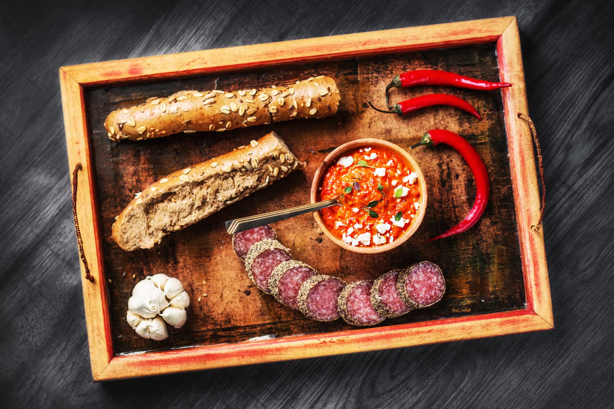 Ajvar served with baguette, garlic, chilli peppers and salami