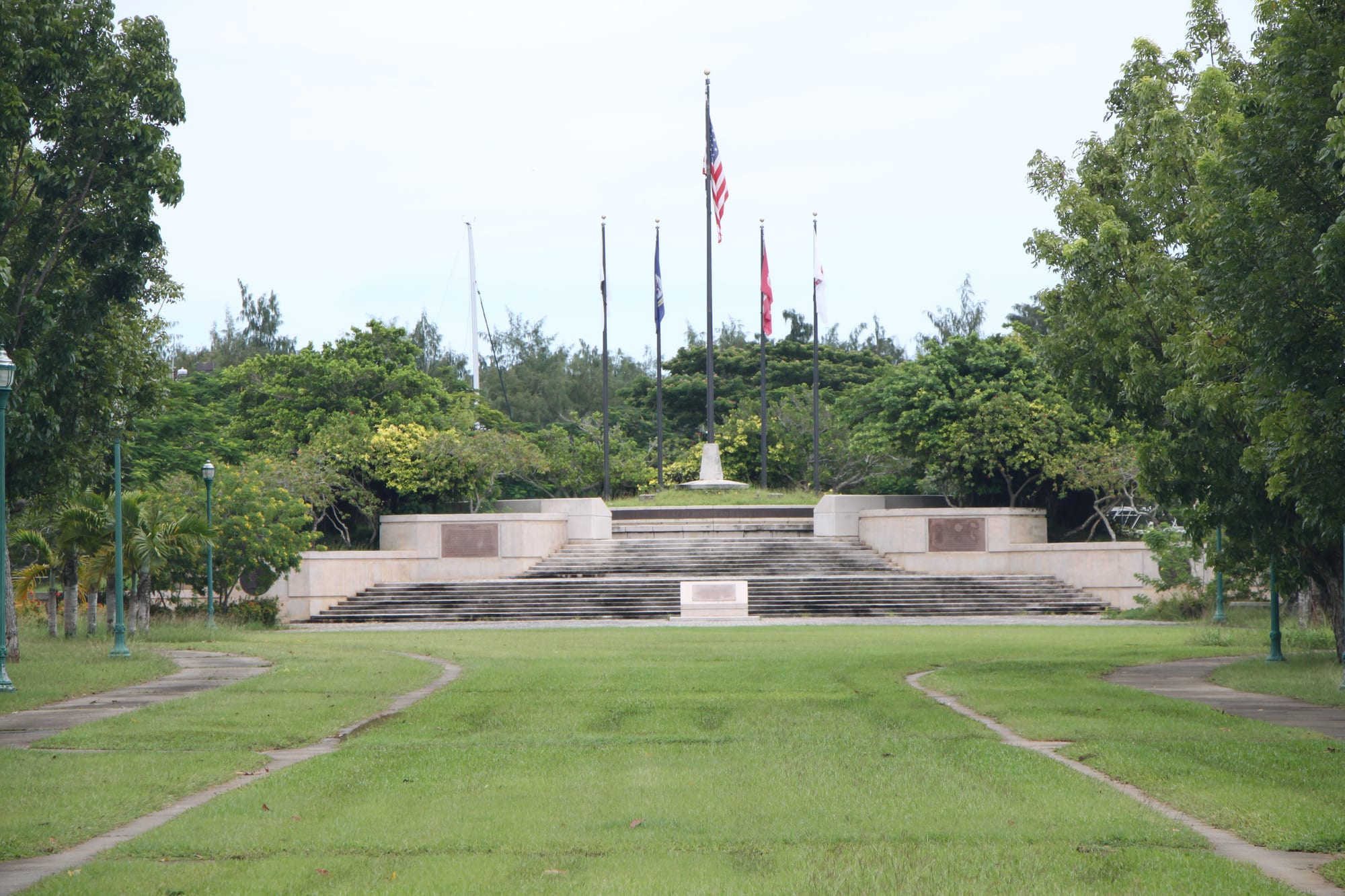 A grassy memorial park with flags and monuments near a marina