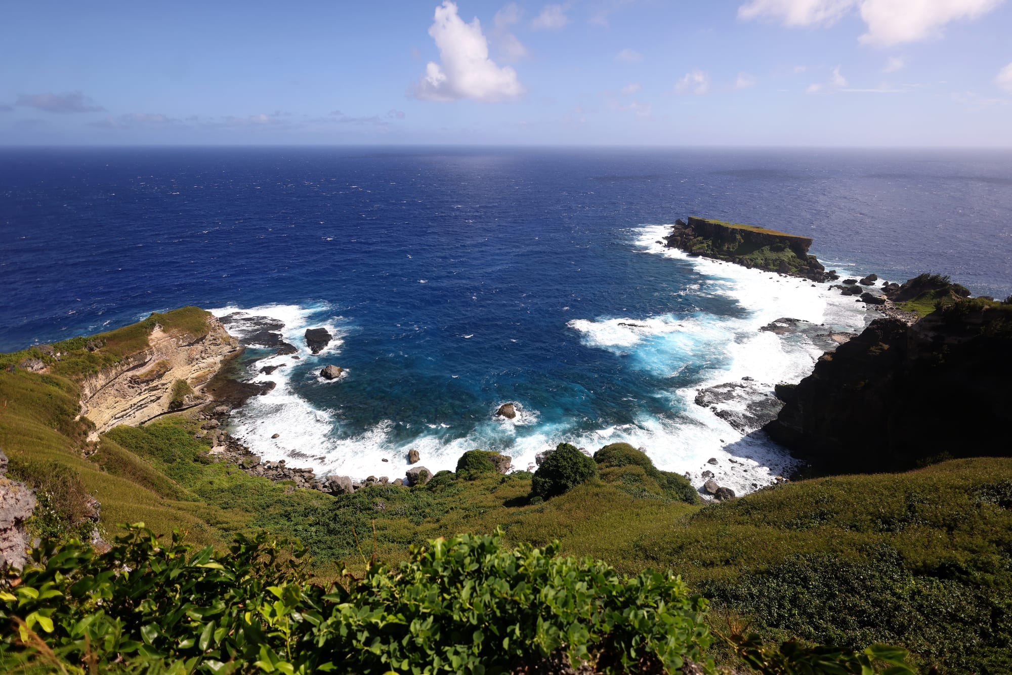 A rugged coastline of cliffs and turquoise water on a tropical Pacific island