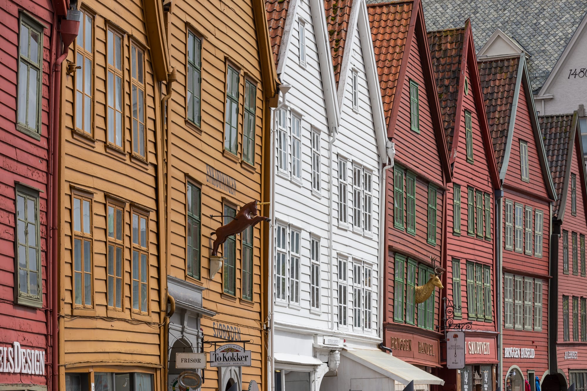 A row of colourful, slightly leaning wooden buildings along a harbour