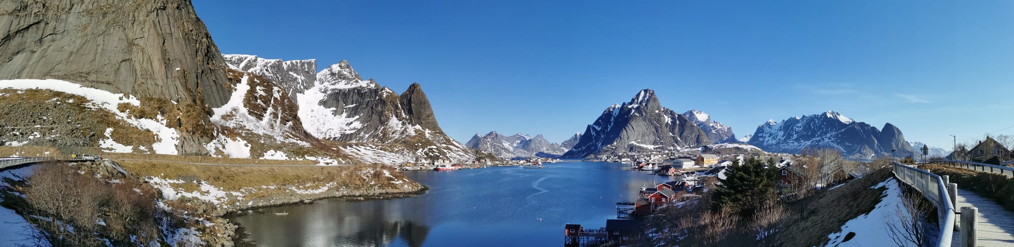 Sharp mountain peaks rising directly from the sea beside a small fishing village