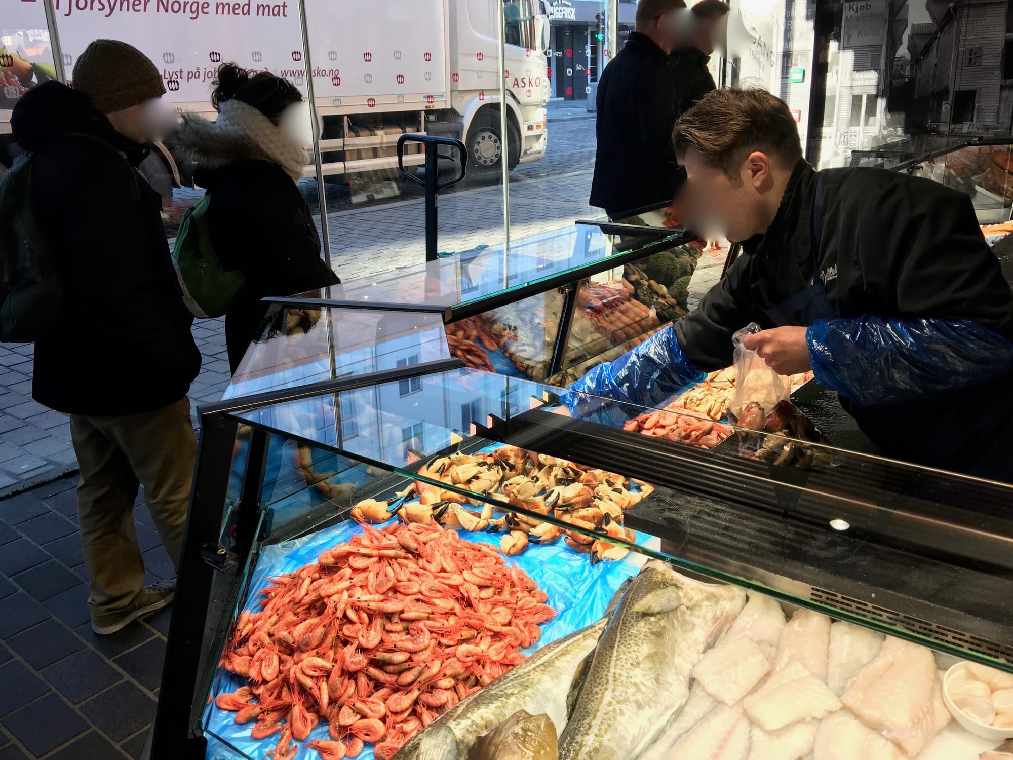 Customers browsing a fresh seafood display counter with shrimp and fish fillets