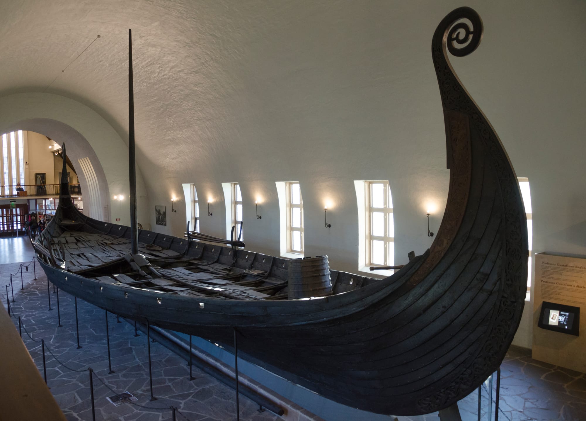 A complete, elegantly curved wooden Viking longship displayed in a museum hall