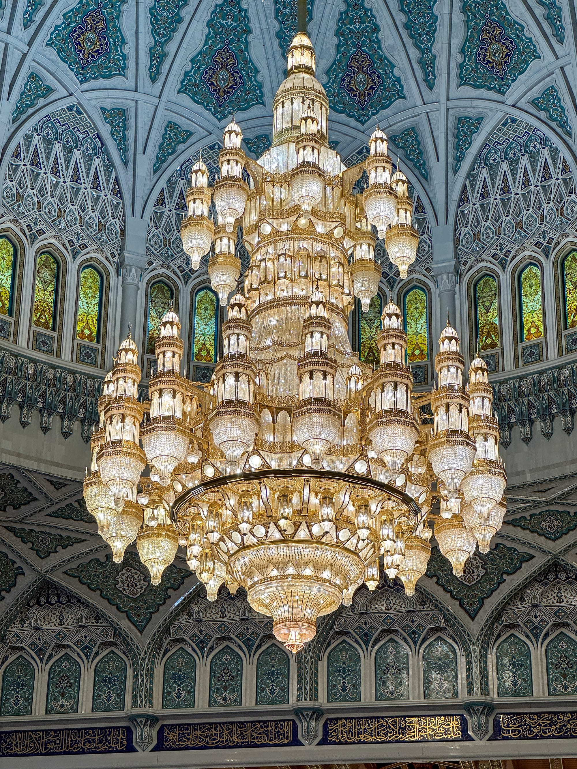 An enormous ornate crystal chandelier hanging inside a mosque's prayer hall