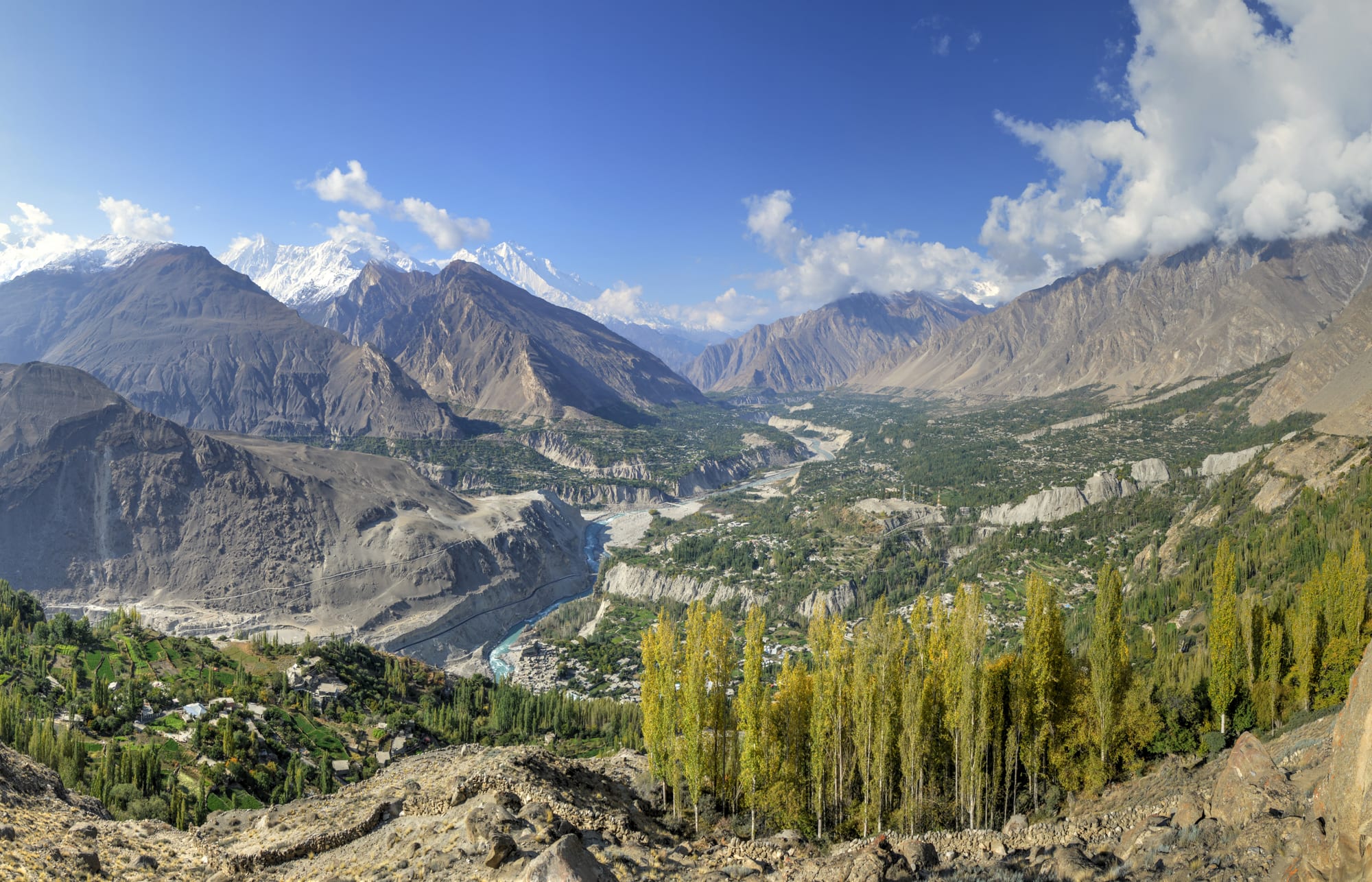 A green terraced valley surrounded by snow-capped mountain peaks