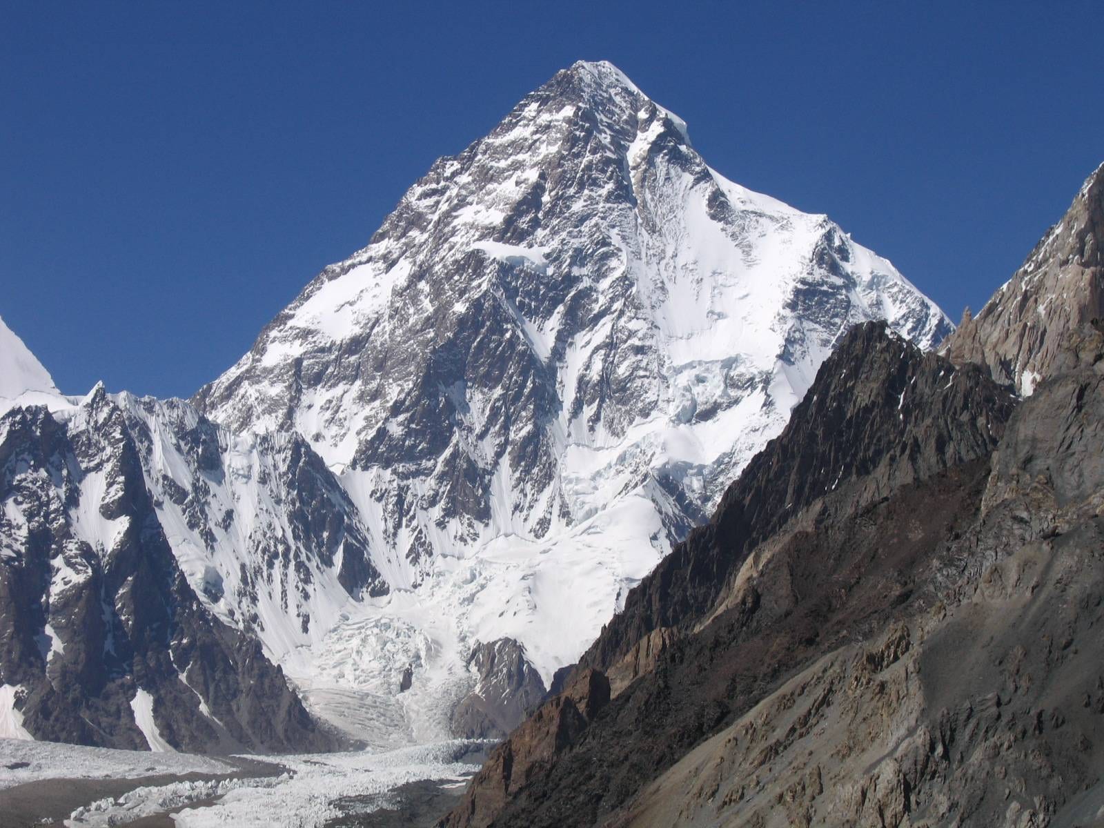A massive pyramidal snow-covered peak rising above a glacier