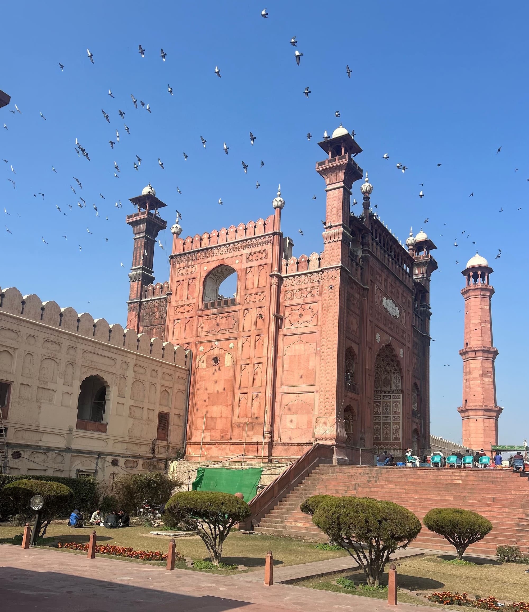 The vast courtyard of a red sandstone mosque filled with worshippers