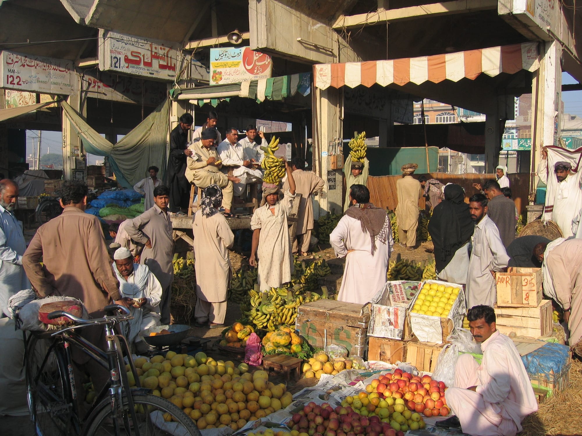 A busy outdoor fruit and vegetable market with vendors and produce