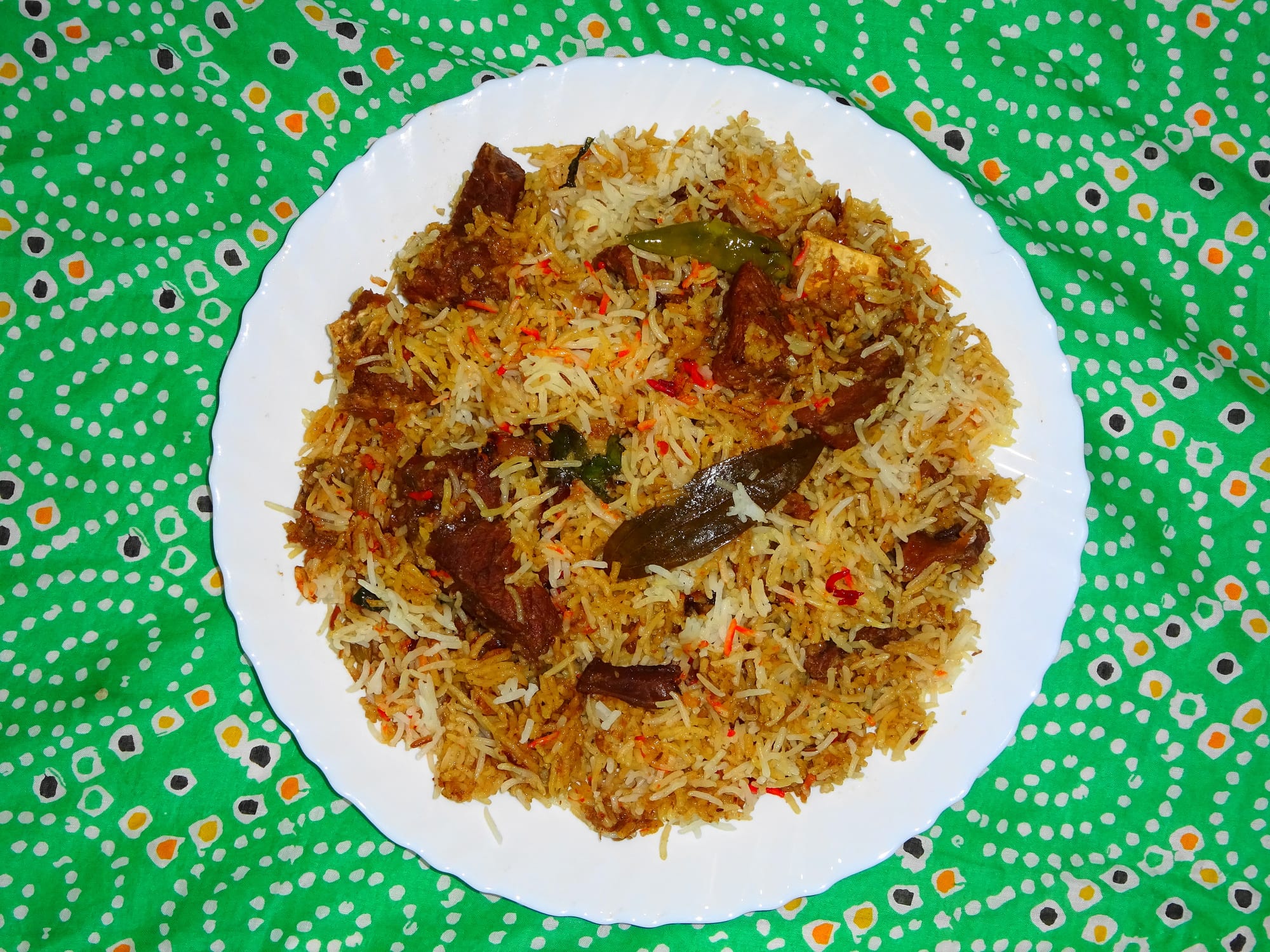 A plate of spiced, layered rice with pieces of meat