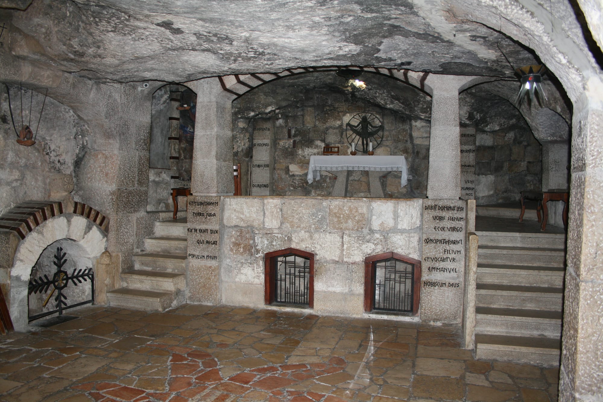 A dimly lit underground grotto with religious icons and lamps