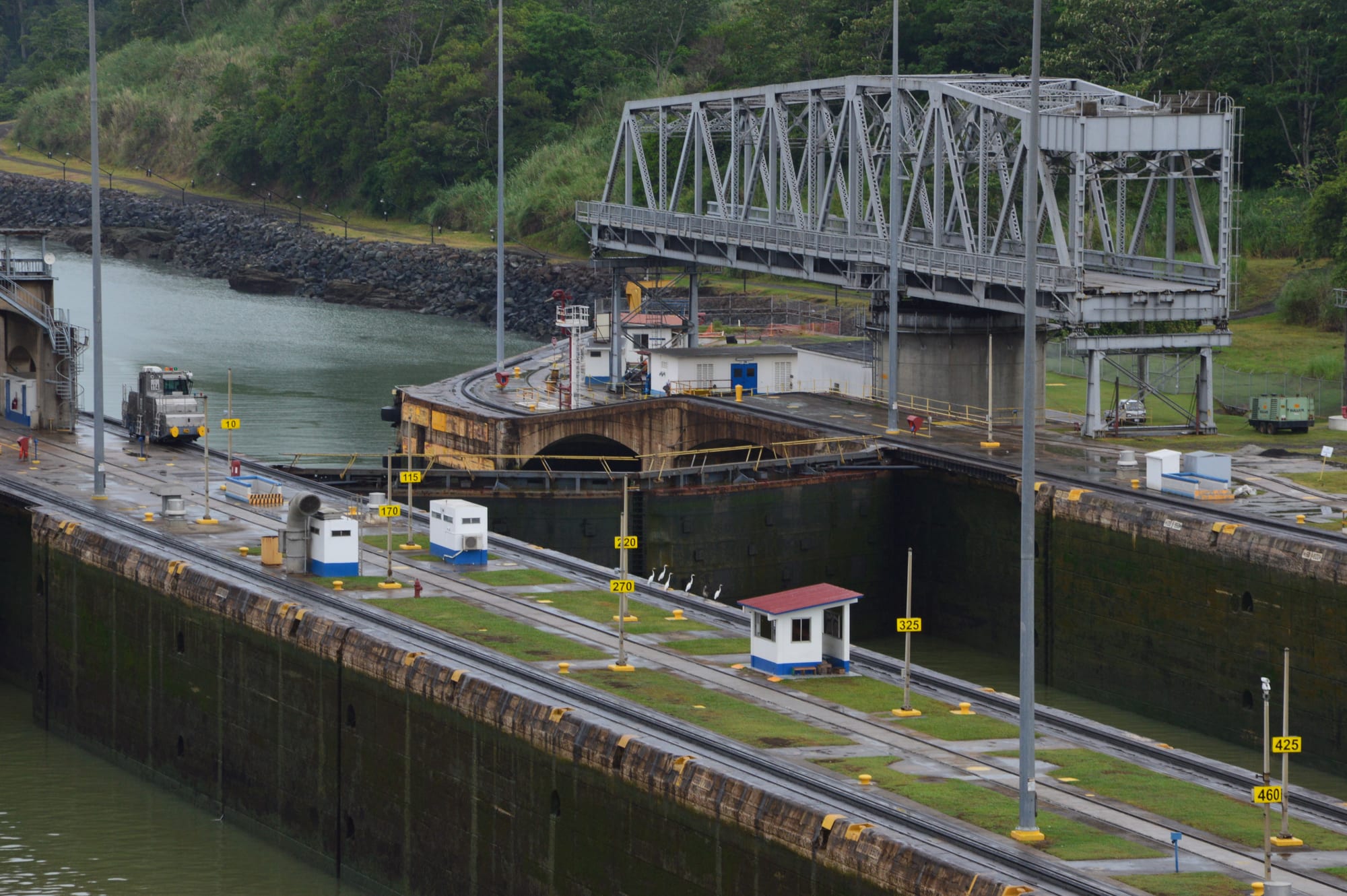 A container ship passing through canal locks flanked by a Panamanian flag