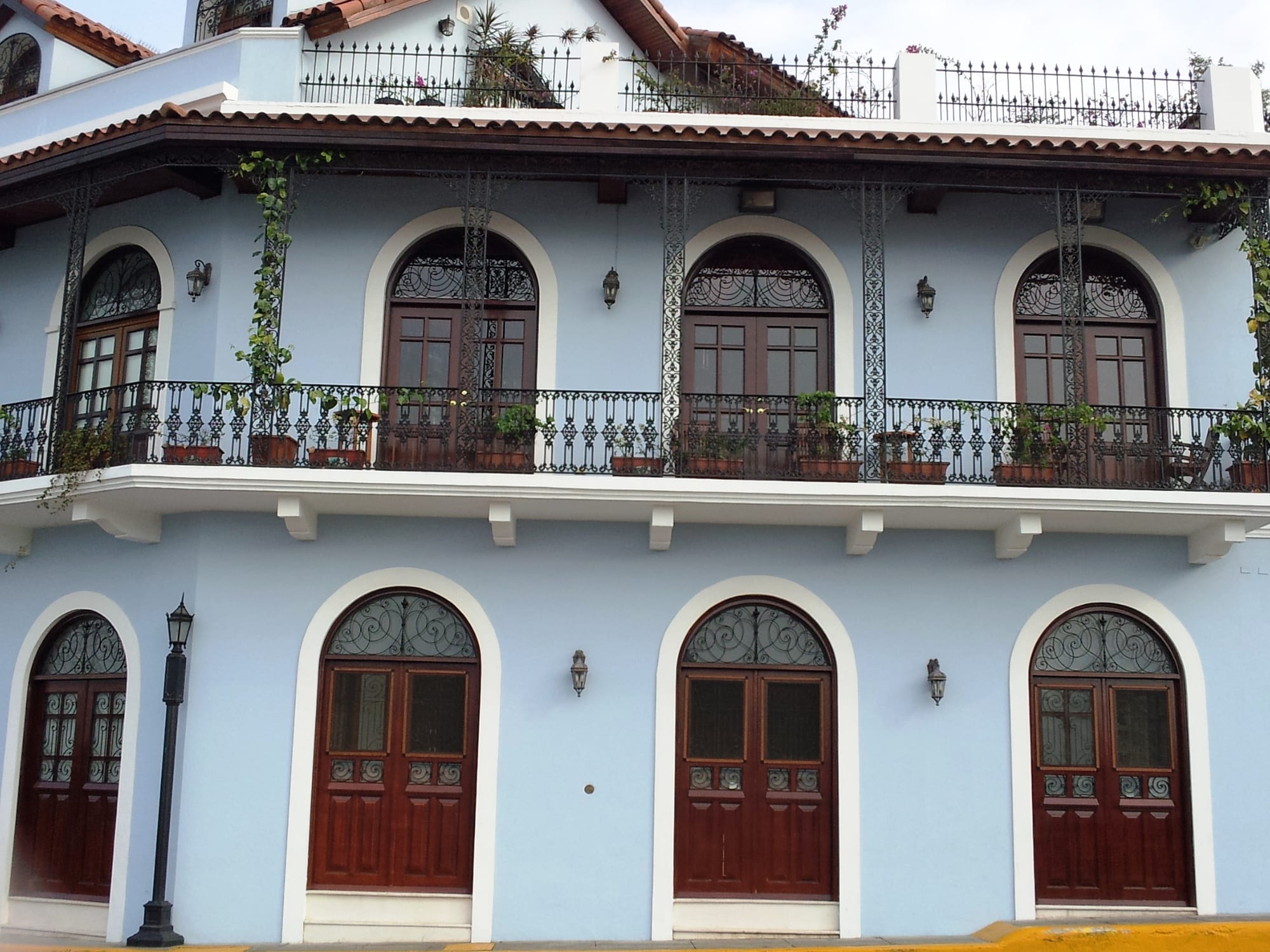 A pastel-blue colonial building with wrought-iron balconies and arched doorways
