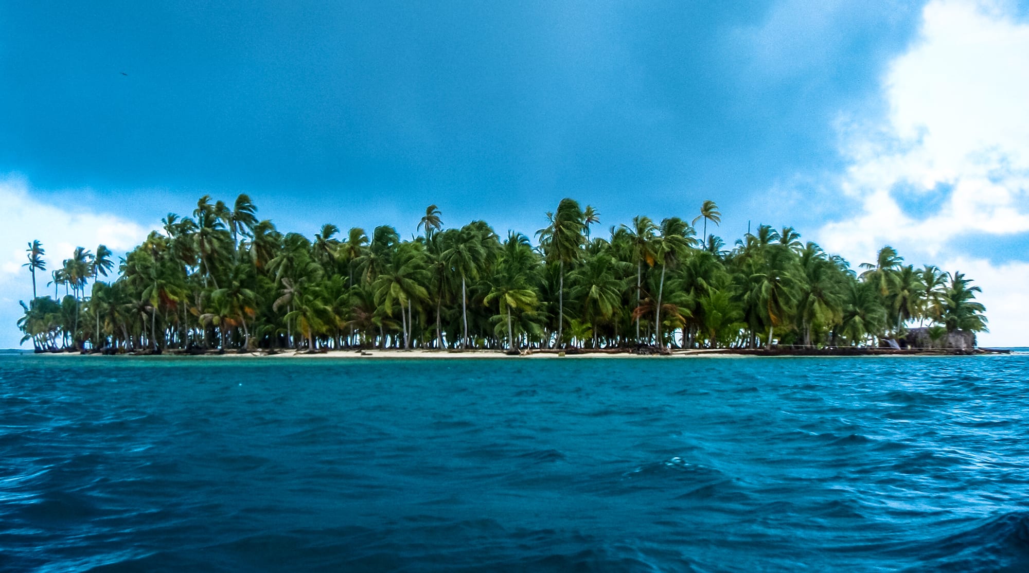 A small palm-covered island surrounded by turquoise Caribbean water