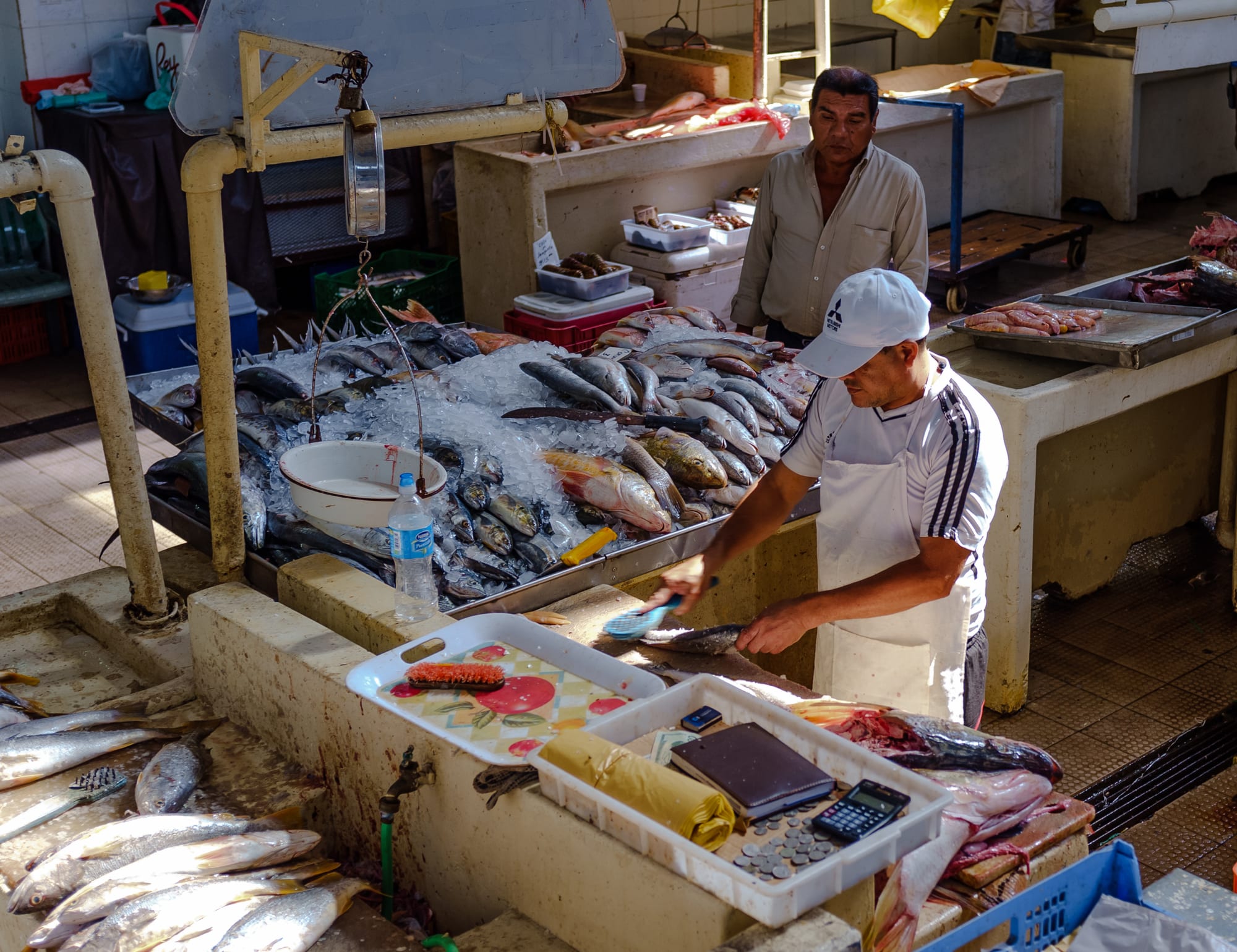 A vendor cutting fresh fish displayed on ice at a fish market