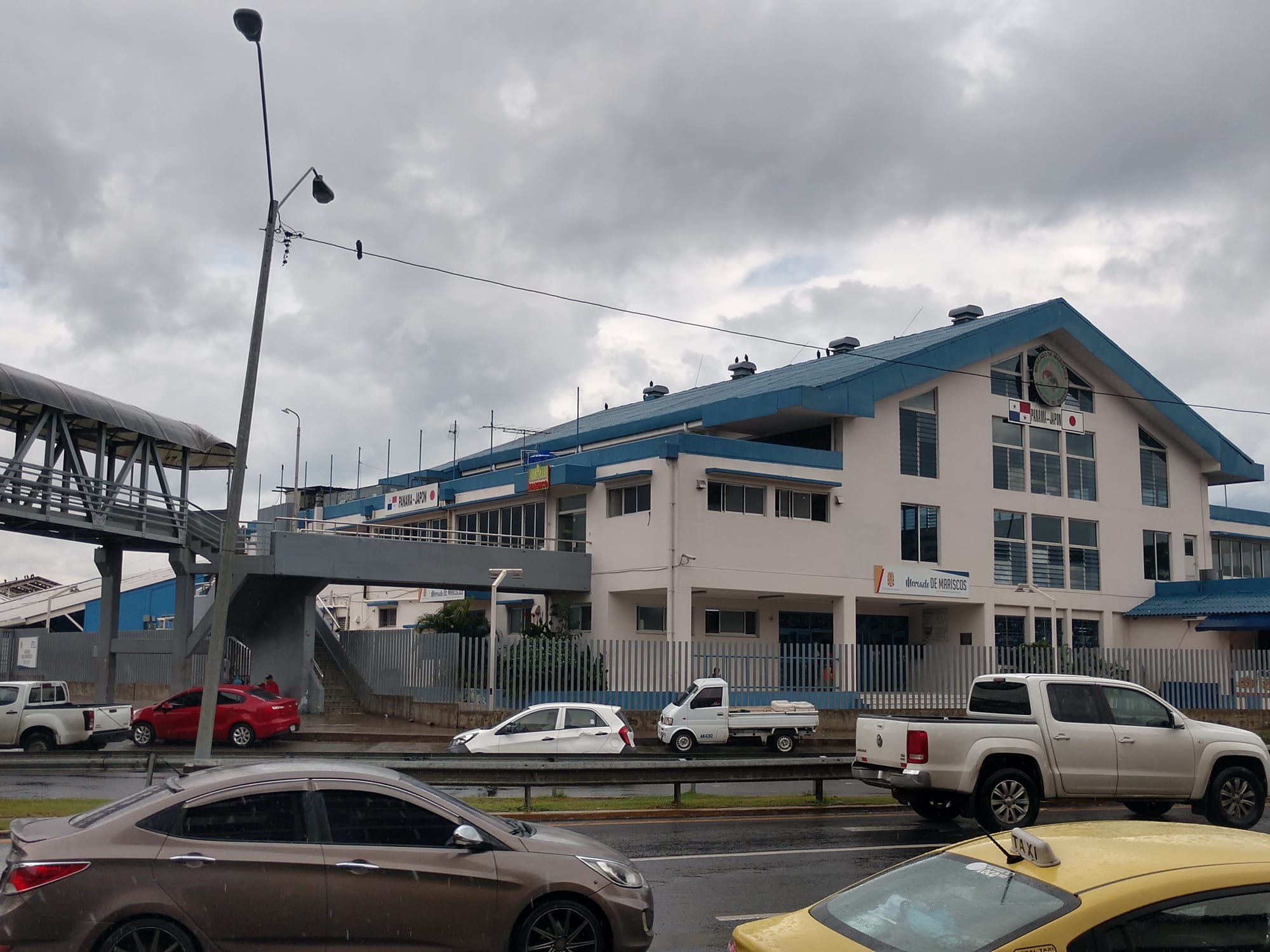 The blue-roofed Mercado de Mariscos seafood market building in Panama City, with cars and a taxi parked outside