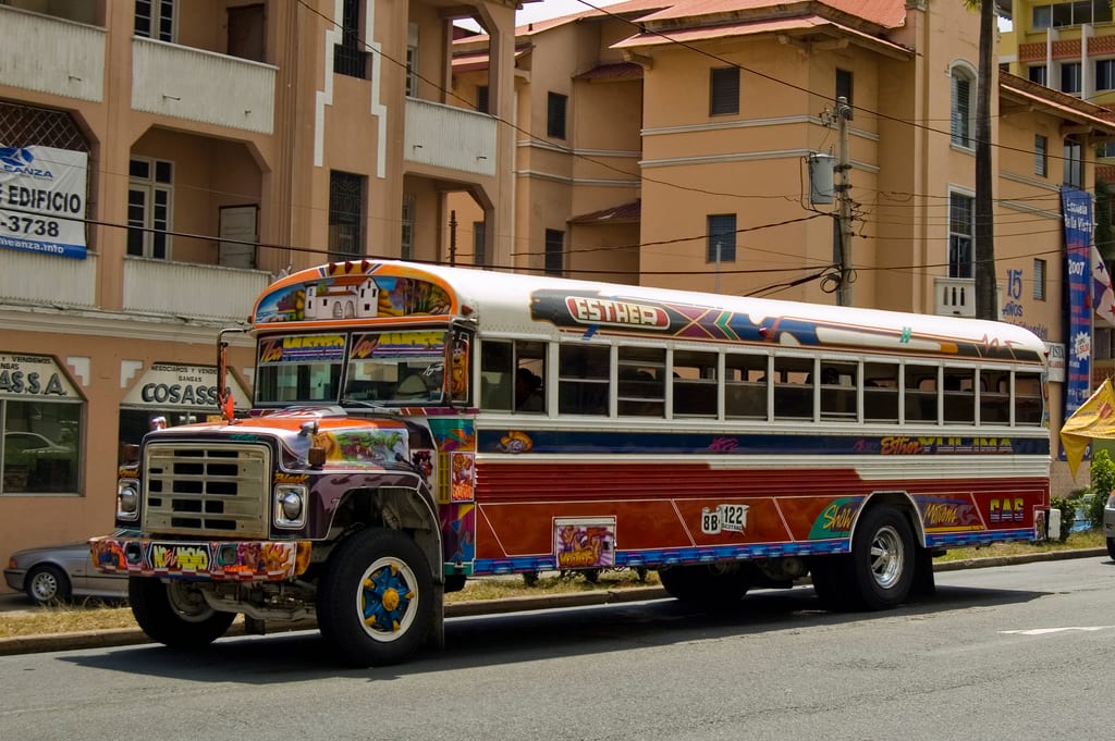 A brightly painted diablo rojo bus, covered in colourful murals and lettering, parked on a Panama City street