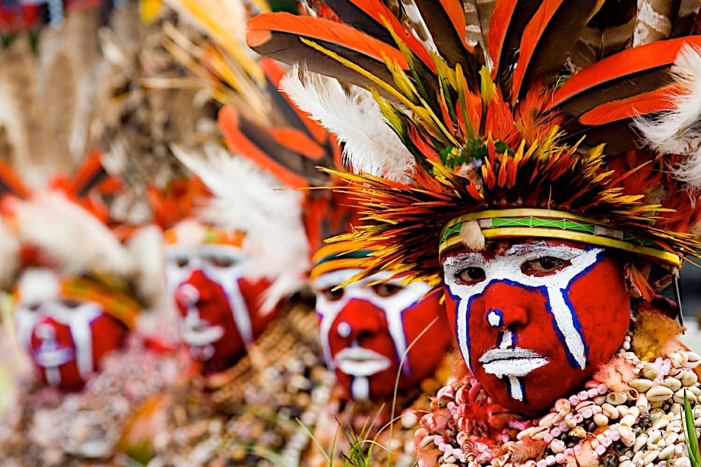 A performer in an elaborate feathered headdress and traditional body paint