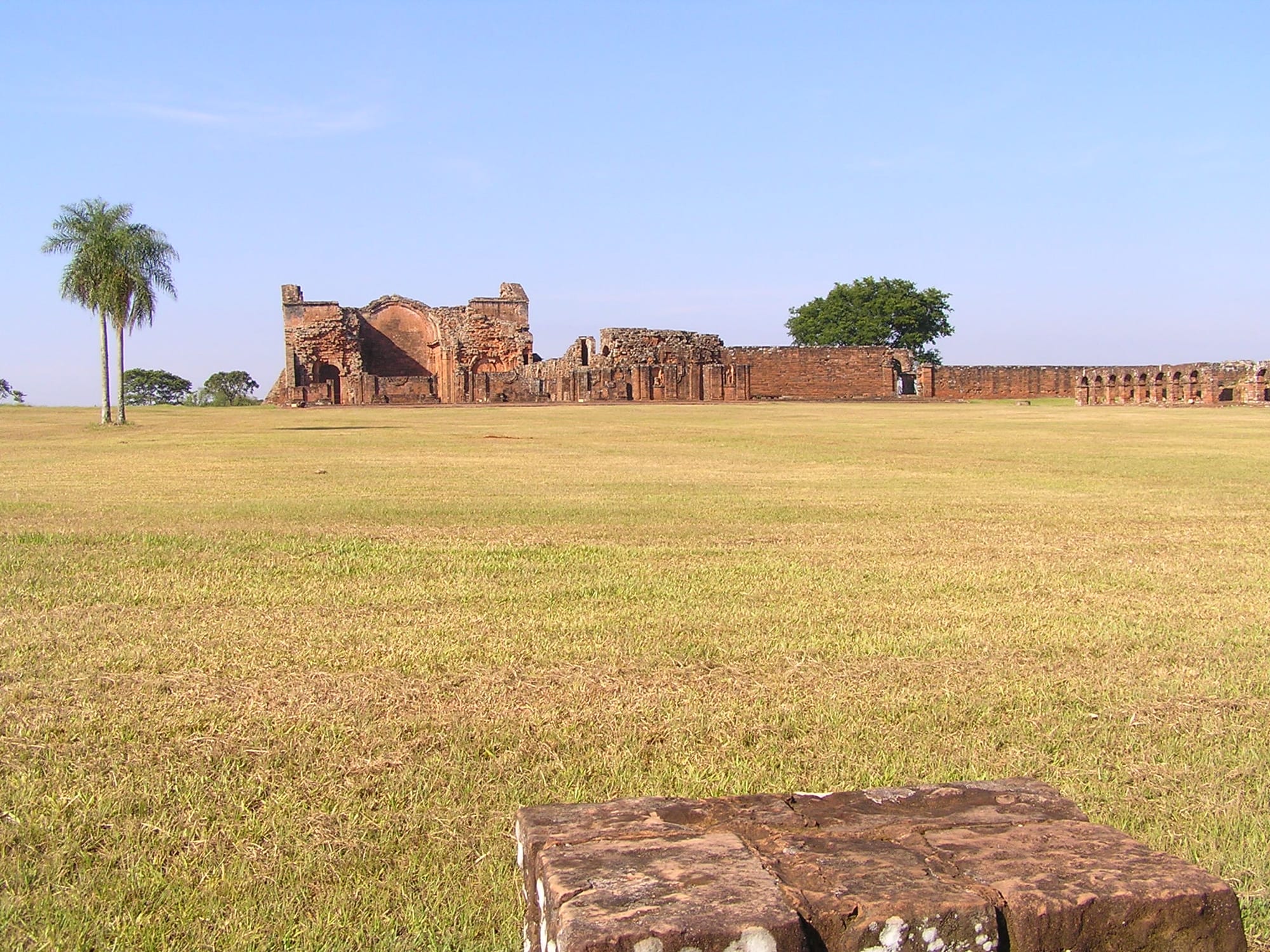 The red sandstone ruins of a large church complex overgrown with grass