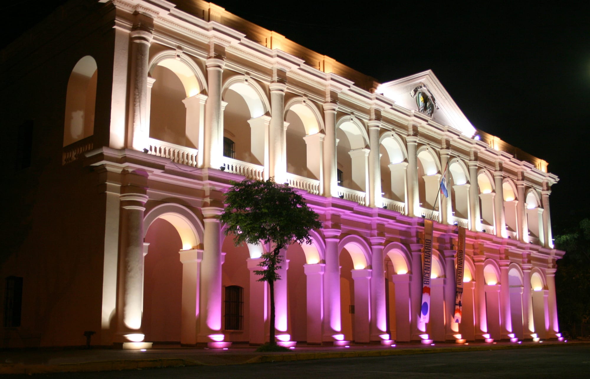 A long colonnaded colonial government building painted white and ochre in central Asunción