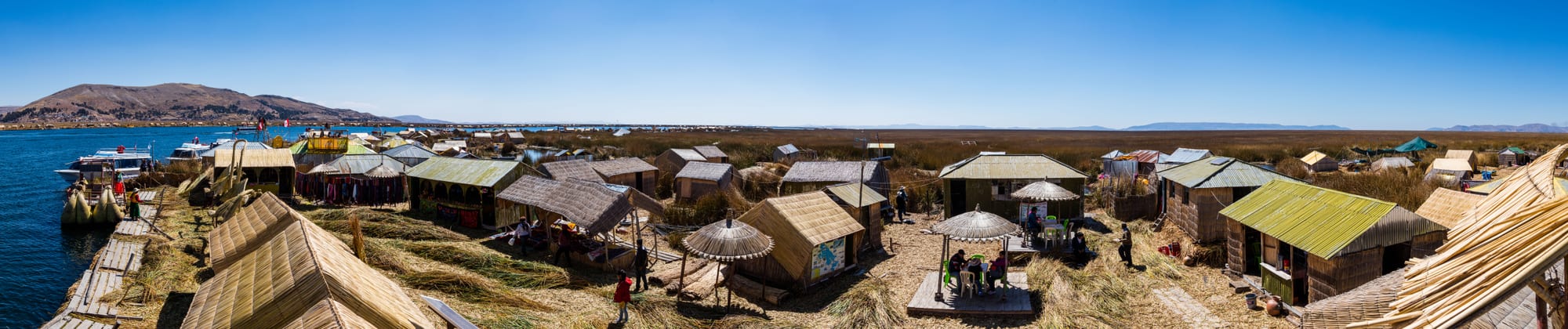 Small artificial islands made of woven reeds floating on a lake, with reed boats
