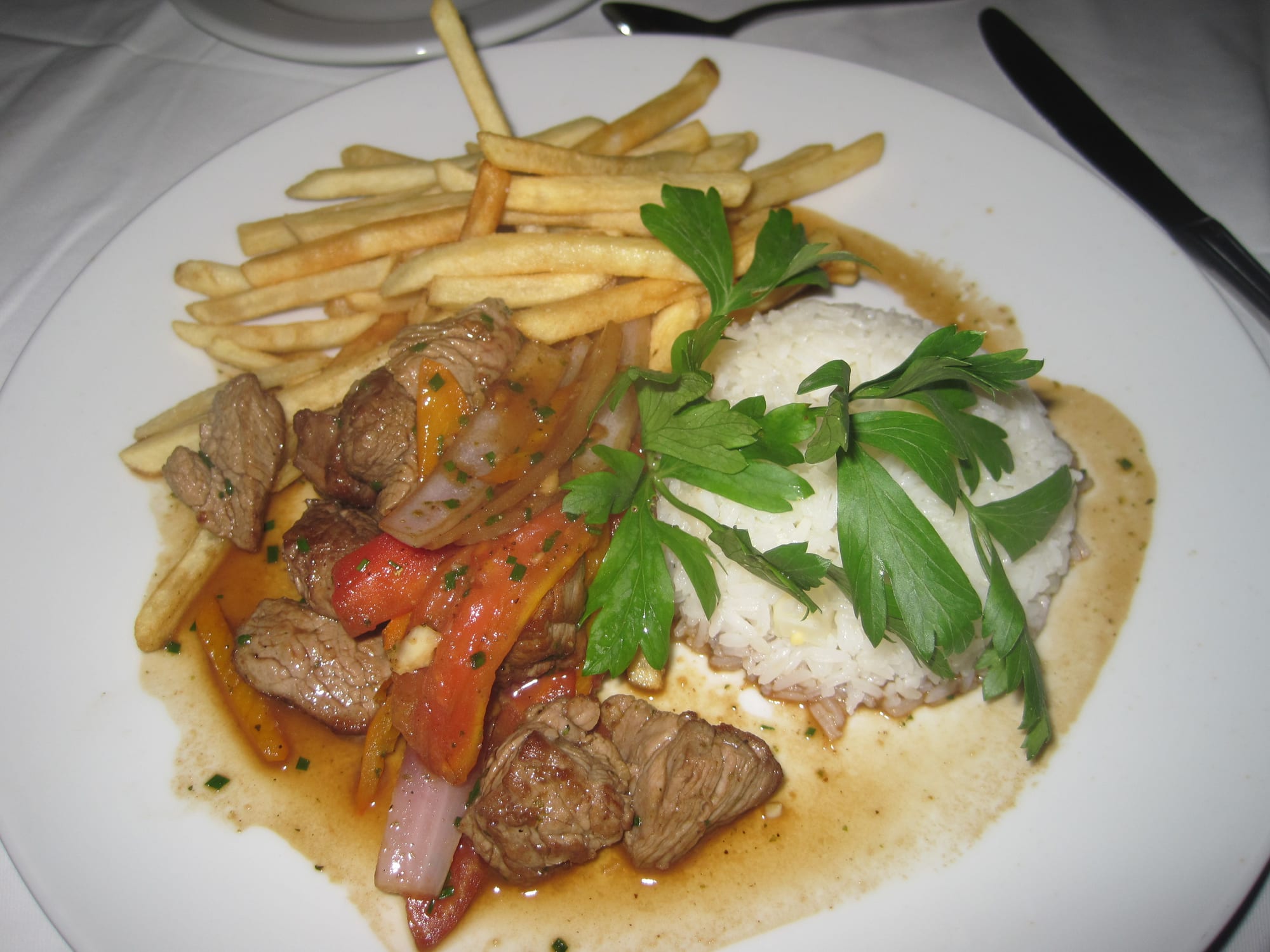 Stir-fried beef with fries and rice, garnished with parsley
