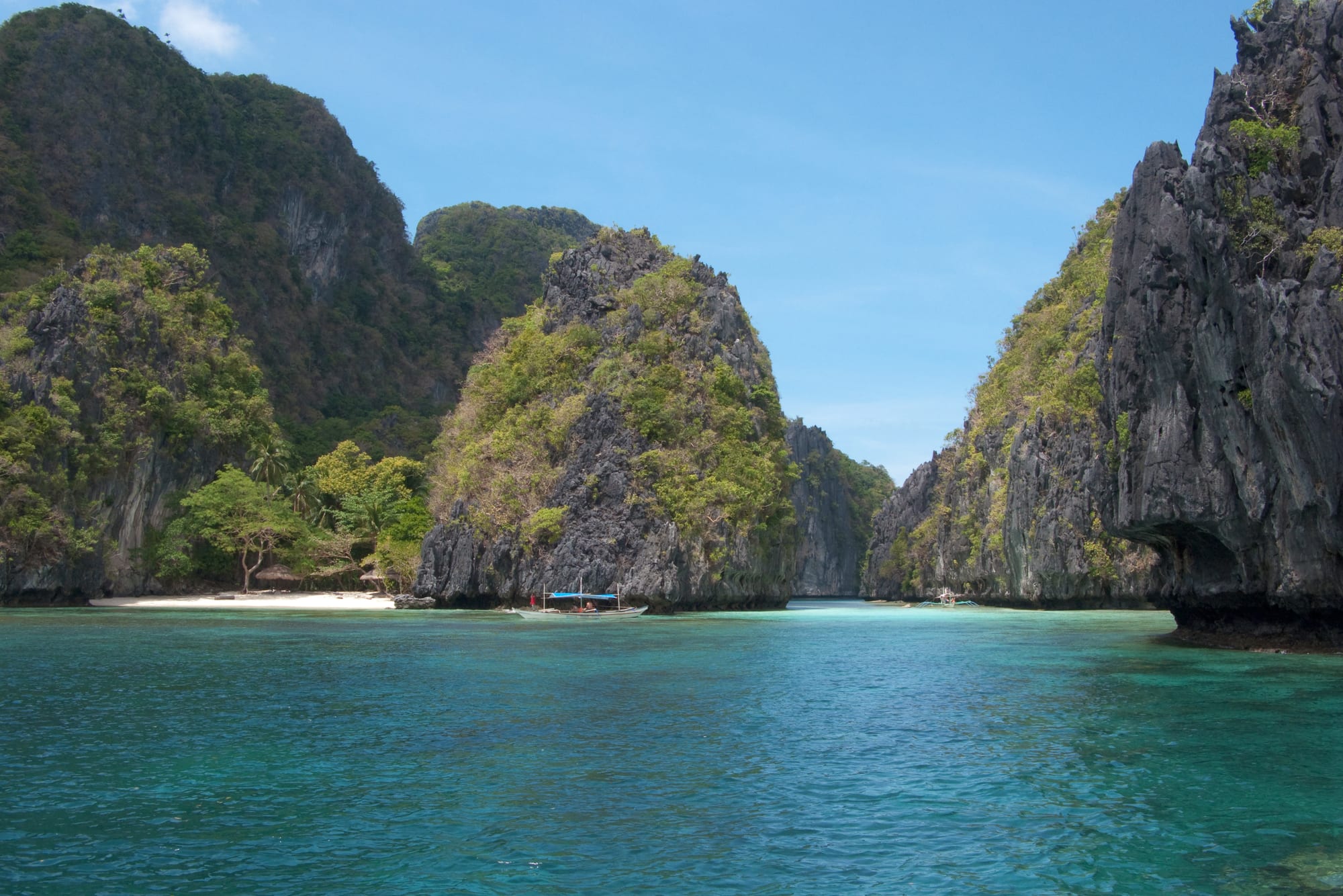A single steep limestone island covered in vegetation rising from clear blue water