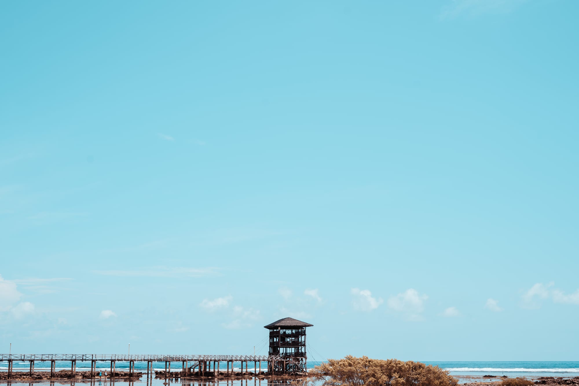 A wooden watchtower and boardwalk over shallow water at a famous surf break