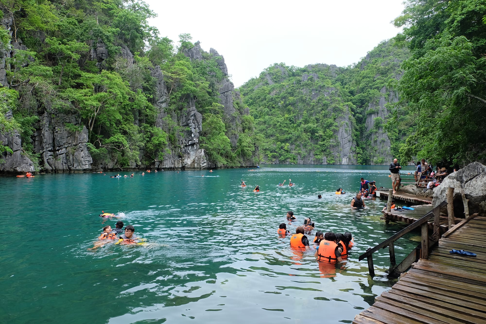 Swimmers in a turquoise lagoon enclosed by sheer limestone cliffs