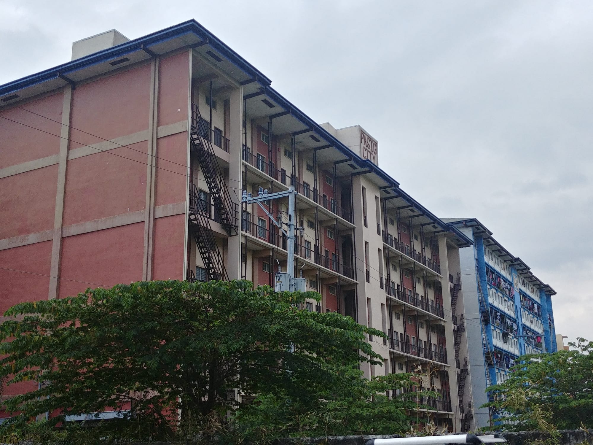 Two multi-storey pink and blue apartment tenement blocks with laundry hanging from the balconies