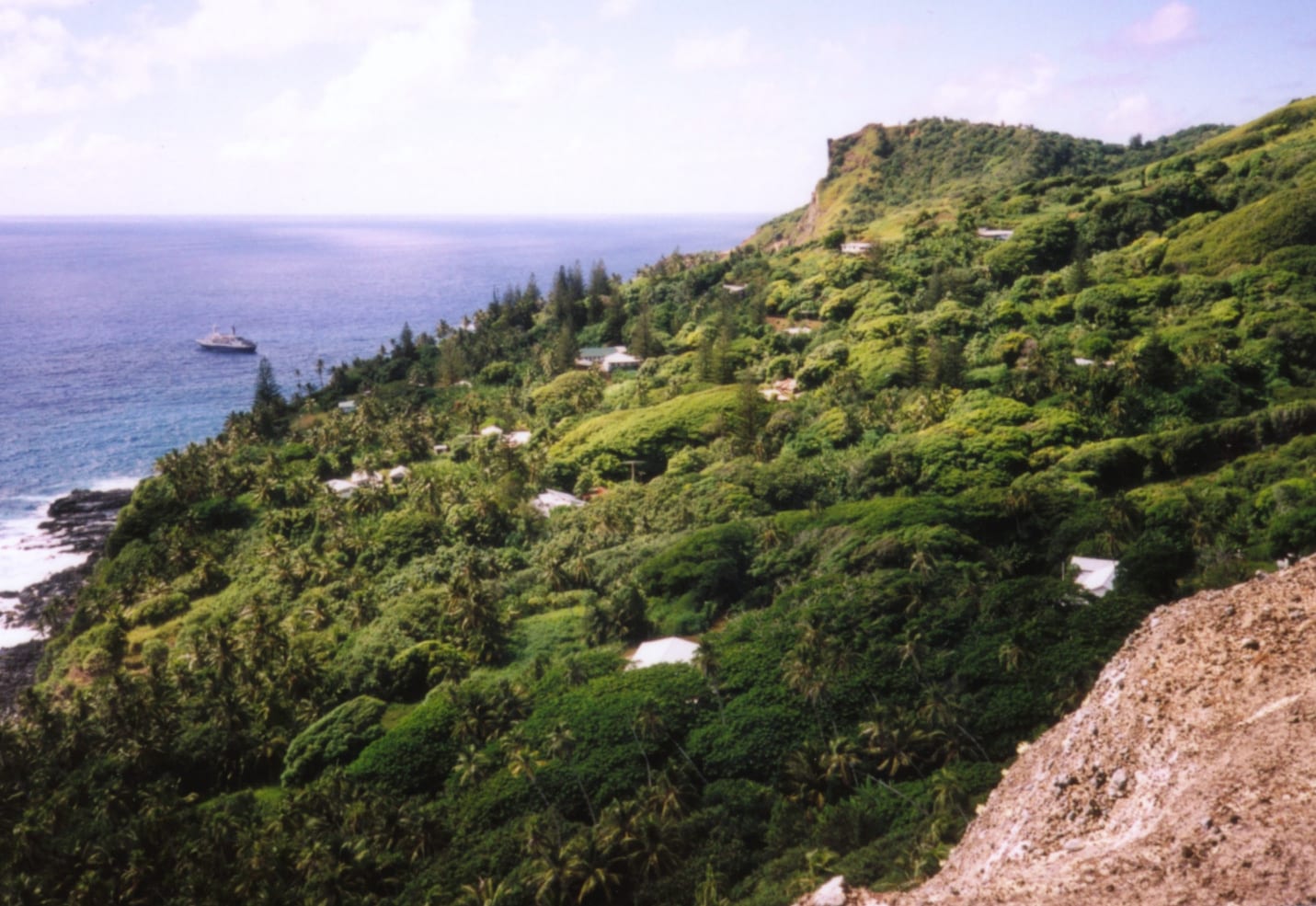 A small settlement of houses among green hillside vegetation