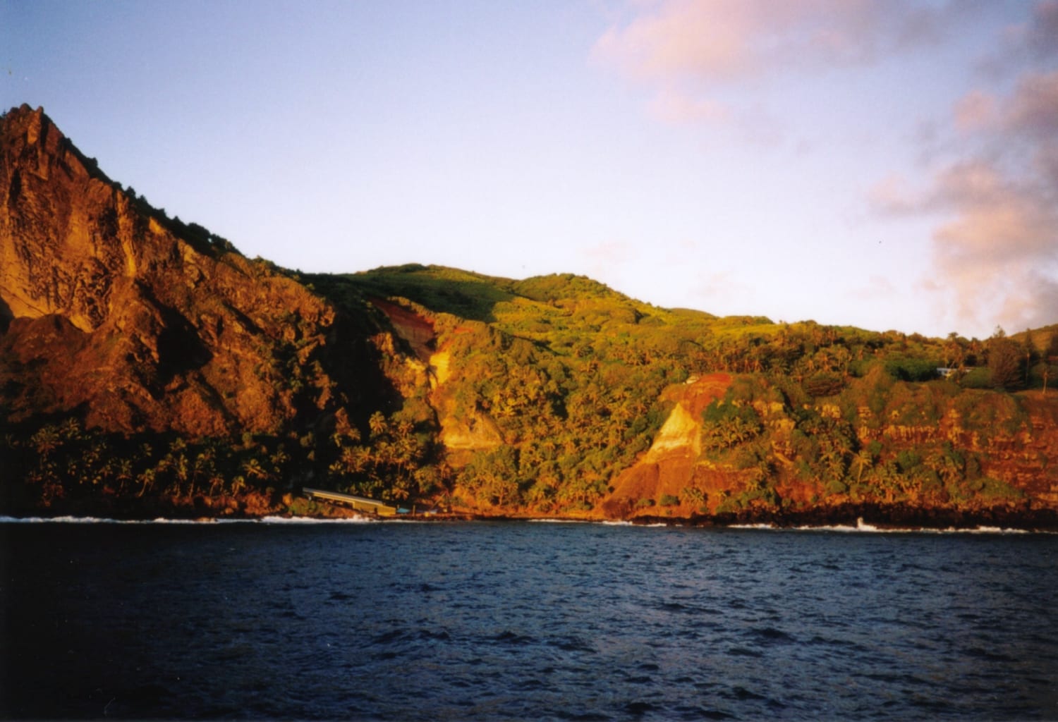 A small rocky bay with a boat landing beneath steep green cliffs