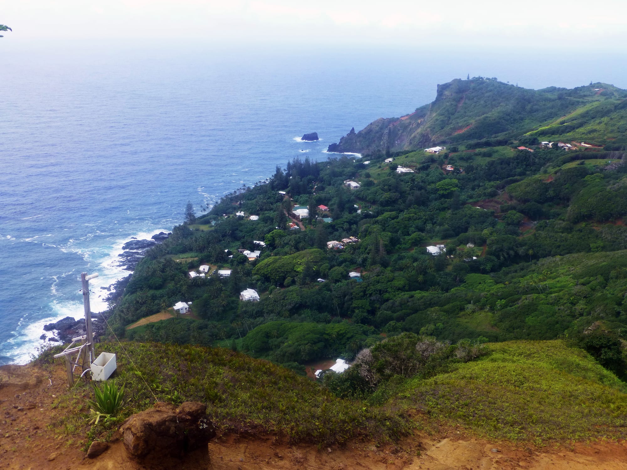 A small settlement of houses on a green hillside above the sea