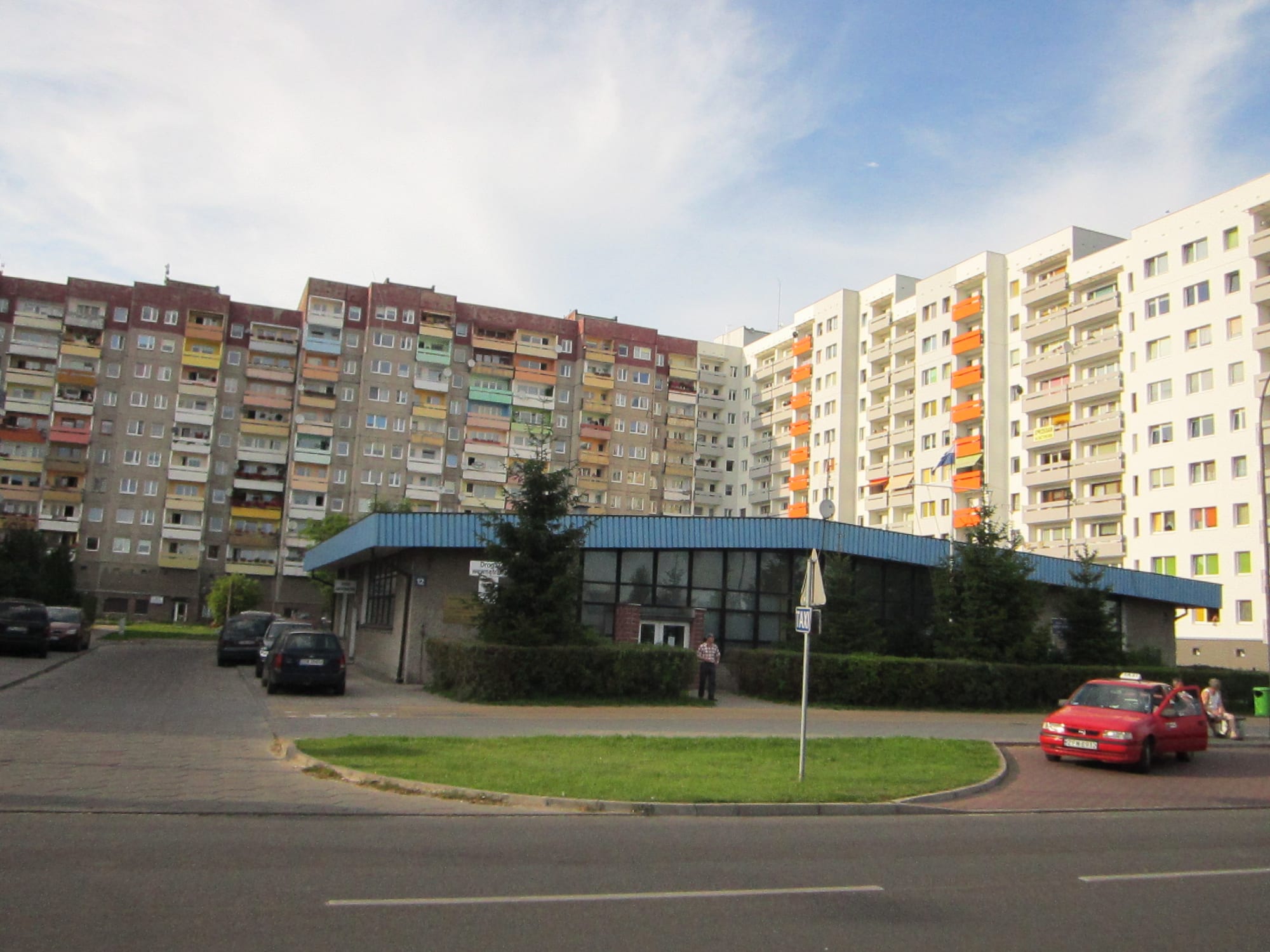 Rows of tall prefabricated concrete apartment blocks with colourful balconies under a blue sky
