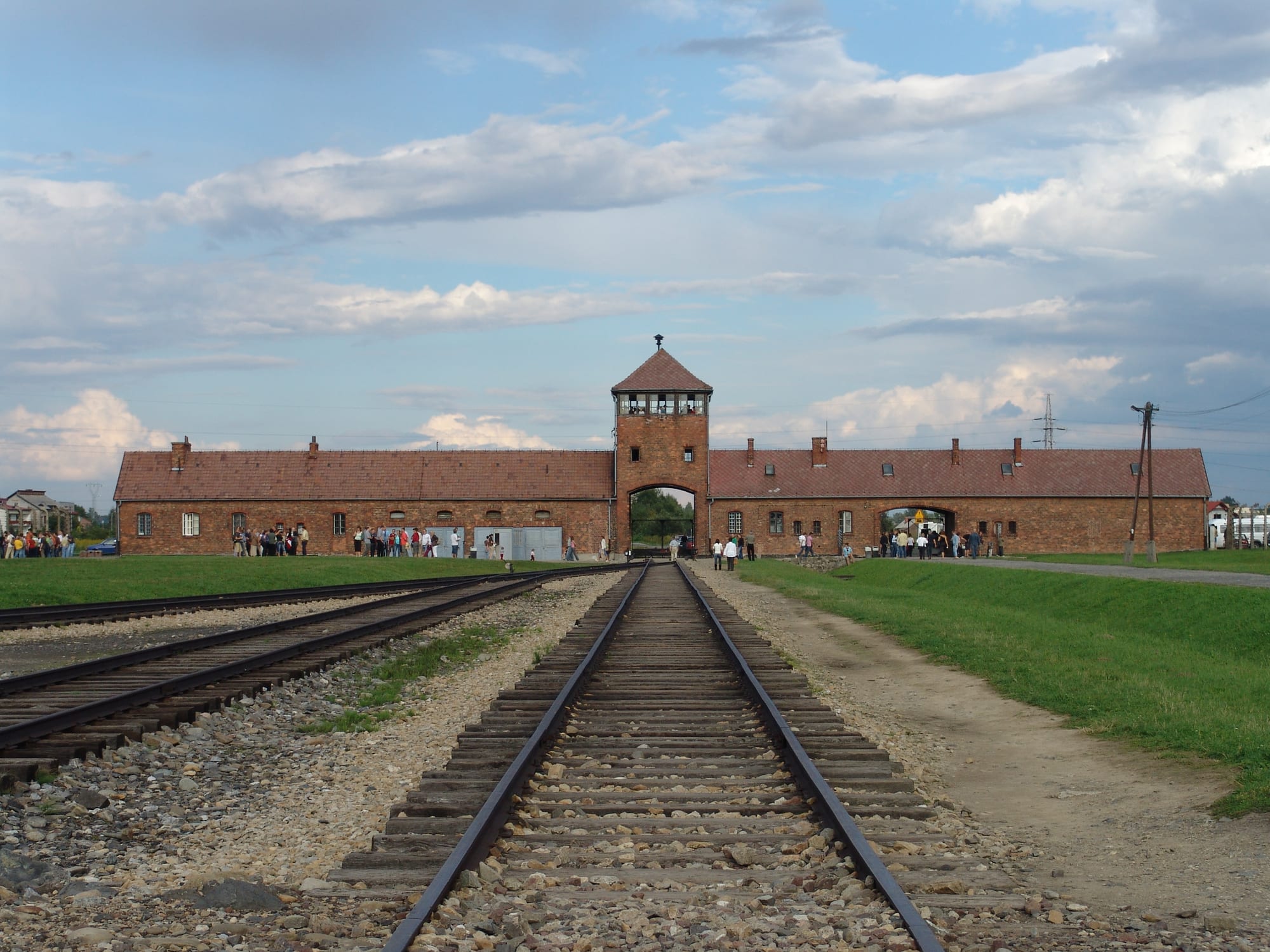 Rail tracks leading through a brick gatehouse into a former concentration camp