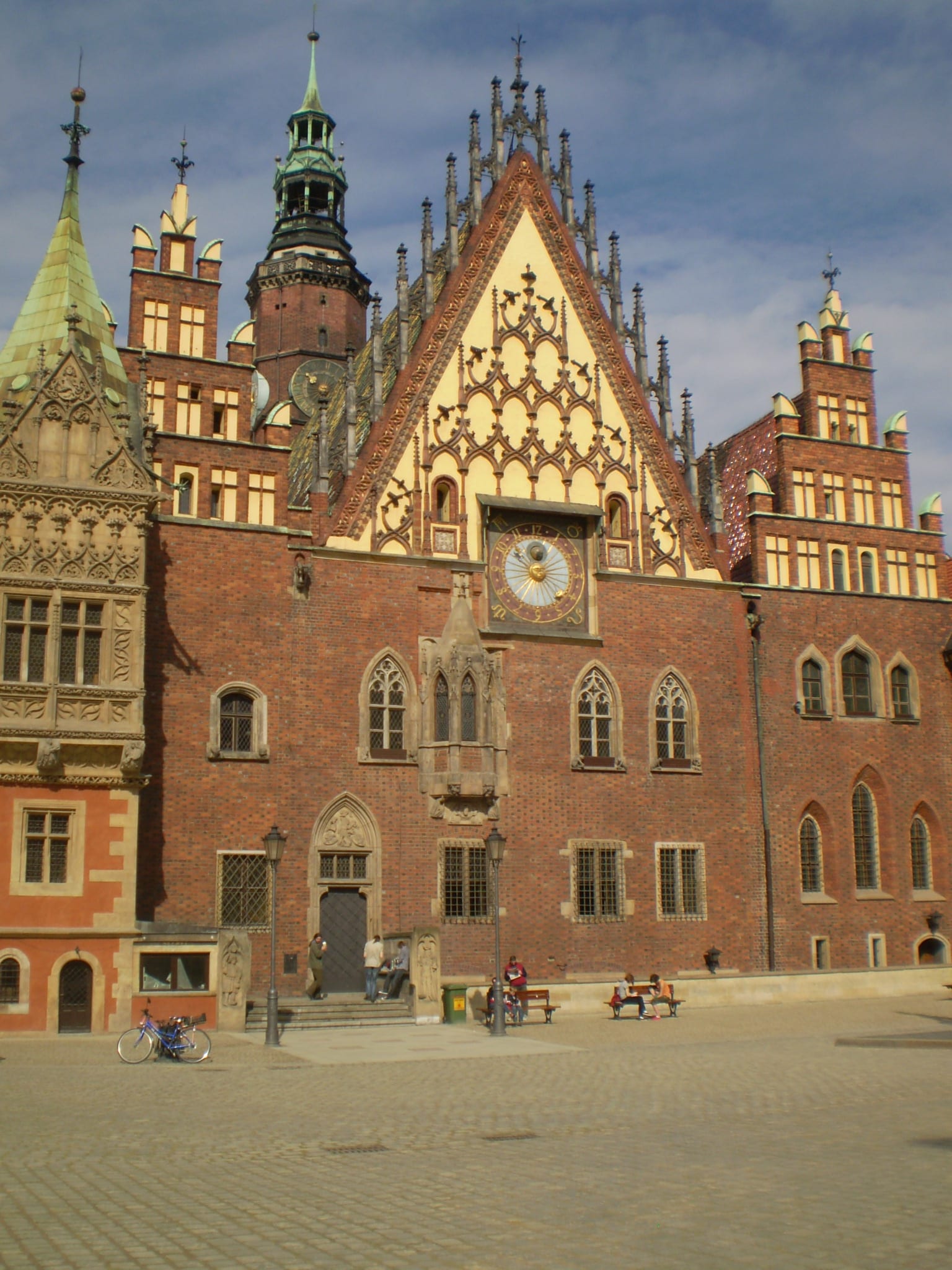 An ornate red-brick Gothic town hall with a spired gable and astronomical clock