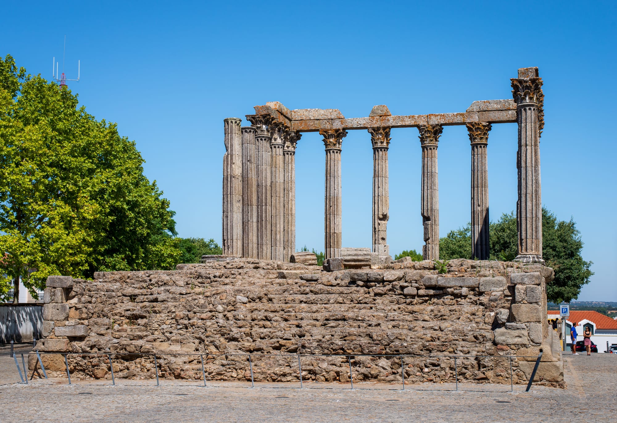 Ancient Roman stone columns standing on a raised platform in a city square