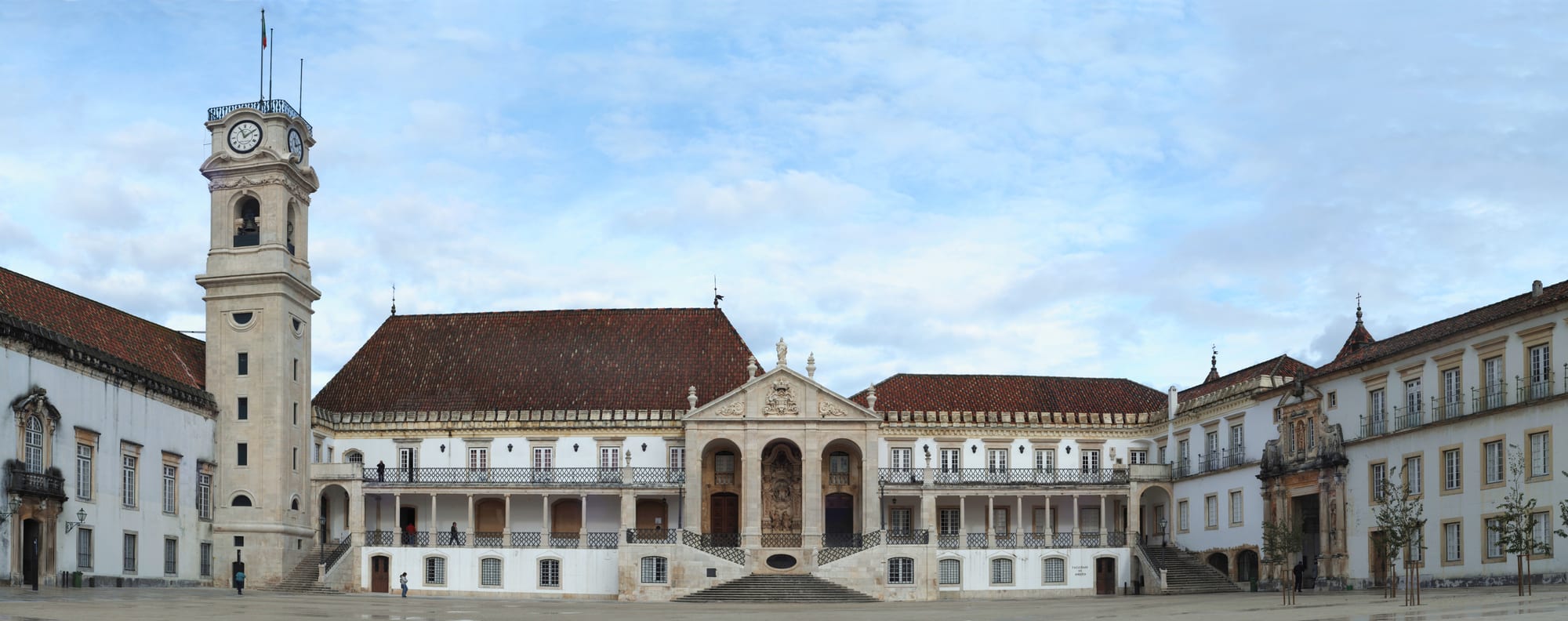 A grand historic university building with a bell tower overlooking a city