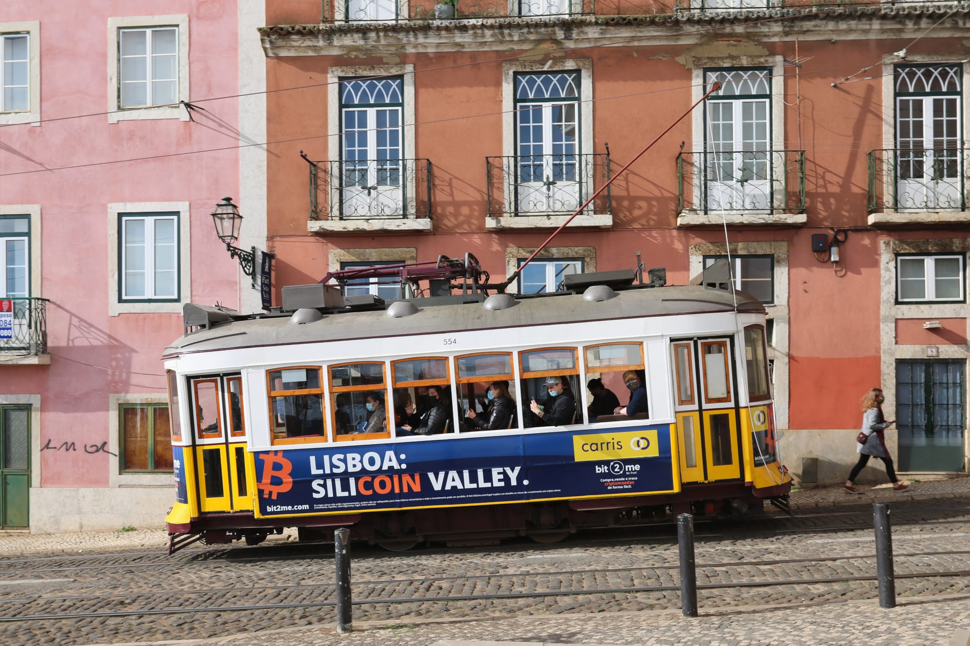 A yellow vintage tram climbing a narrow, hilly cobbled street