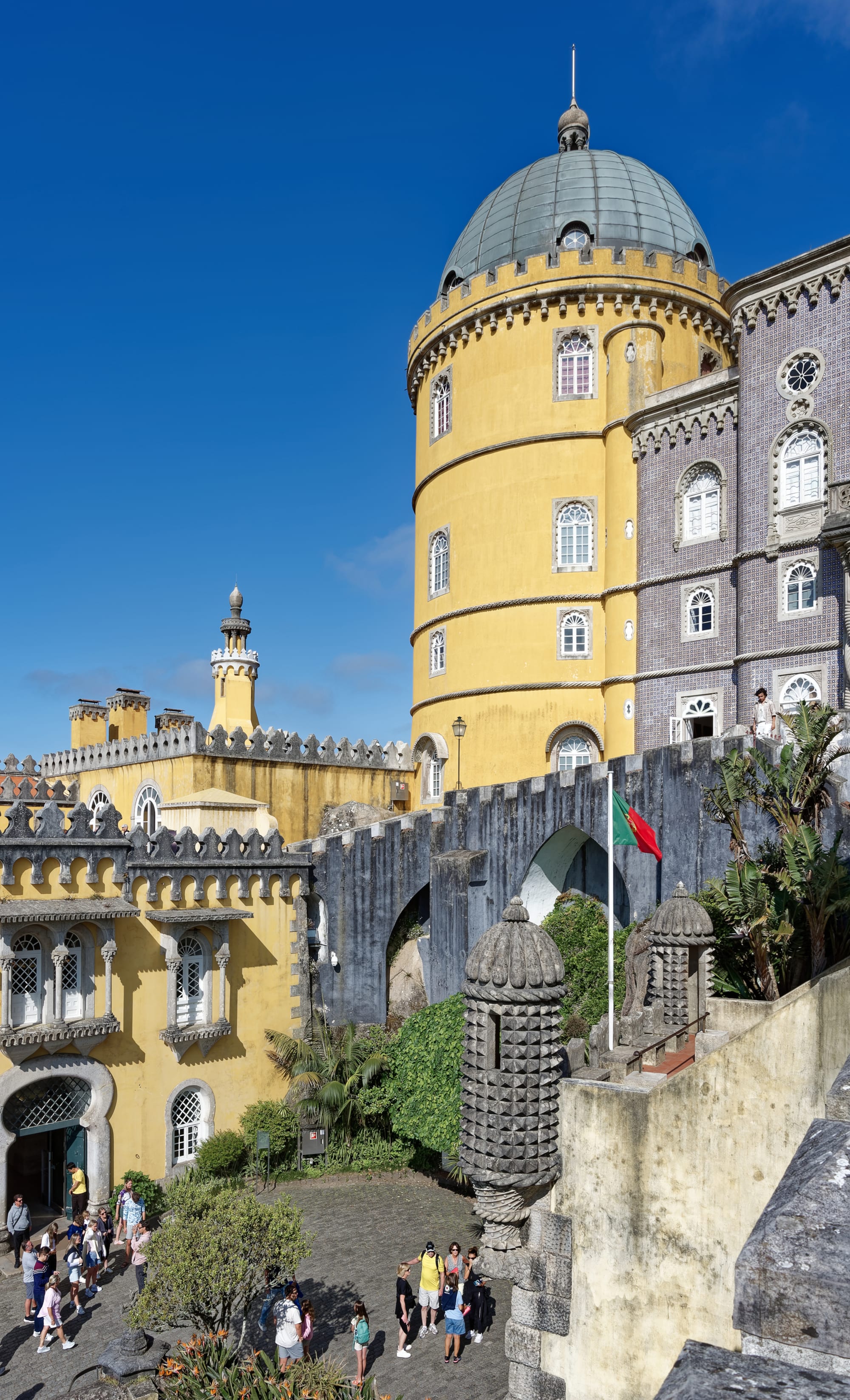A brightly coloured, whimsical palace with towers and domes on a forested hilltop