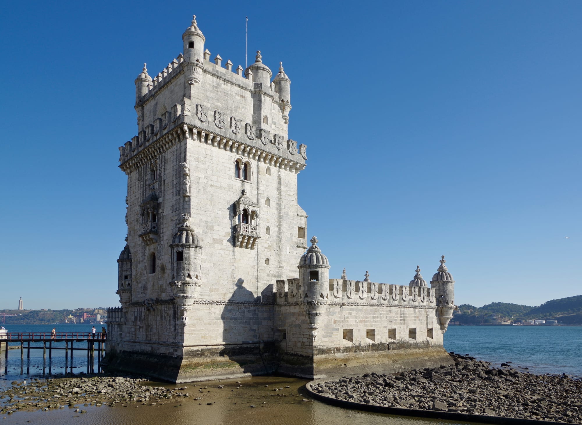 An ornate stone tower with turrets standing beside a wide river