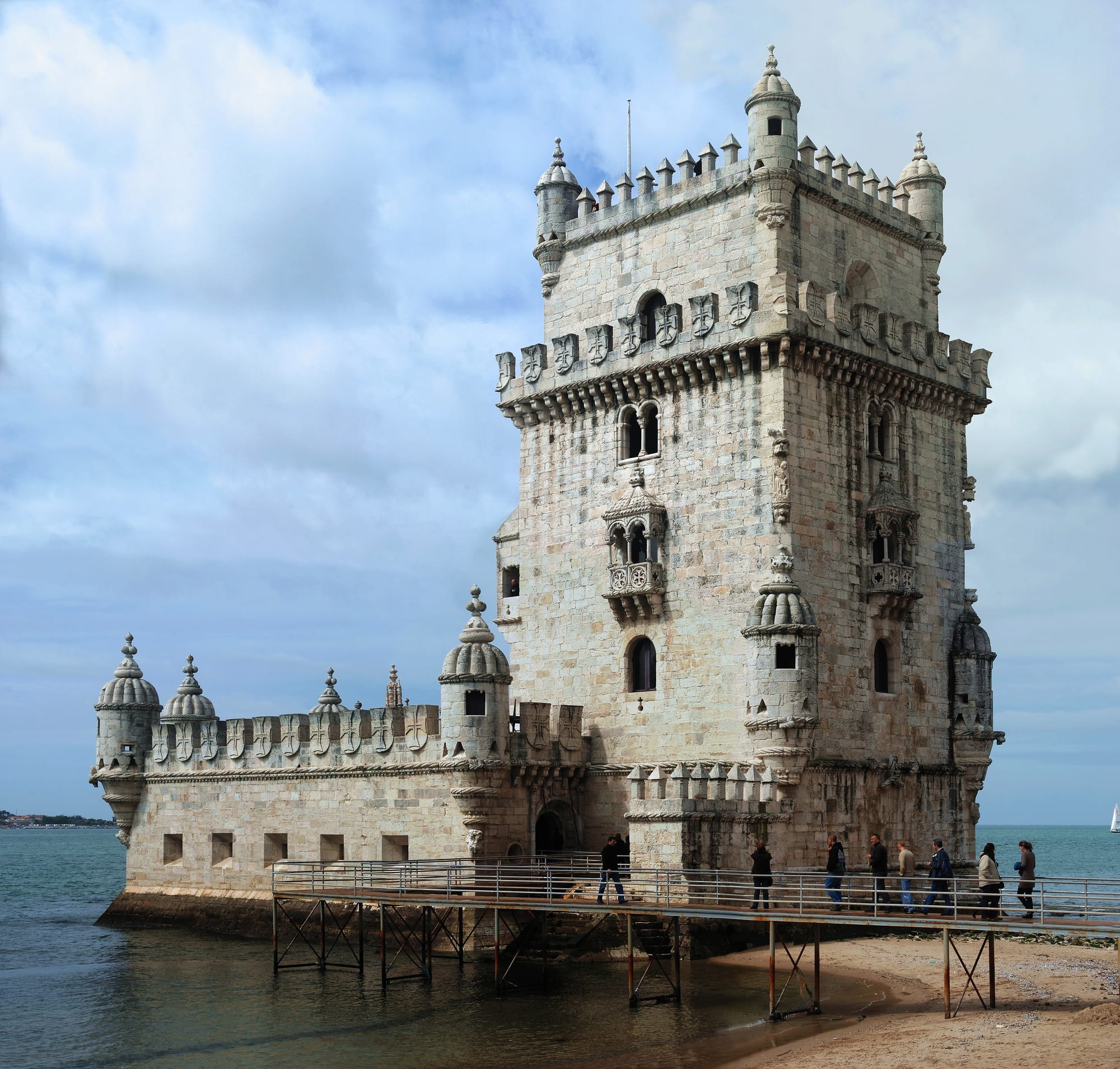 The ornate white limestone Belém Tower standing in the water at the edge of the Tagus in Lisbon