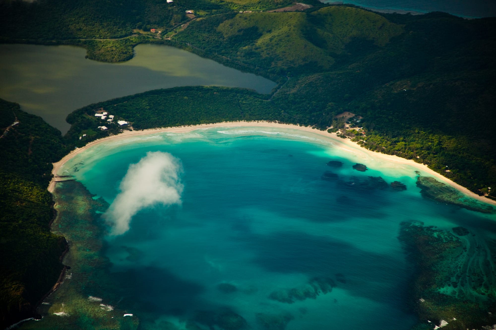A crescent white sand beach with clear turquoise water