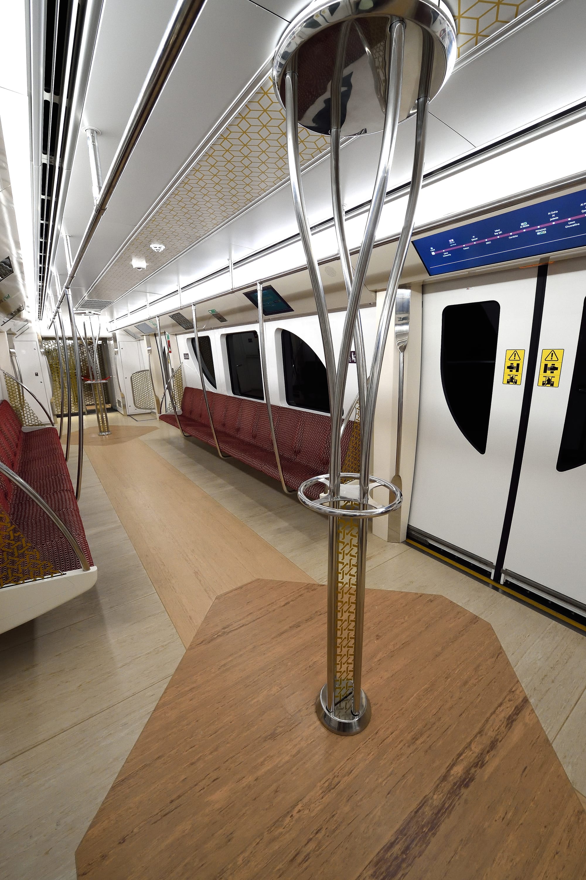 The clean, modern interior of a Doha Metro train carriage, with patterned ceiling panels and red upholstered seating