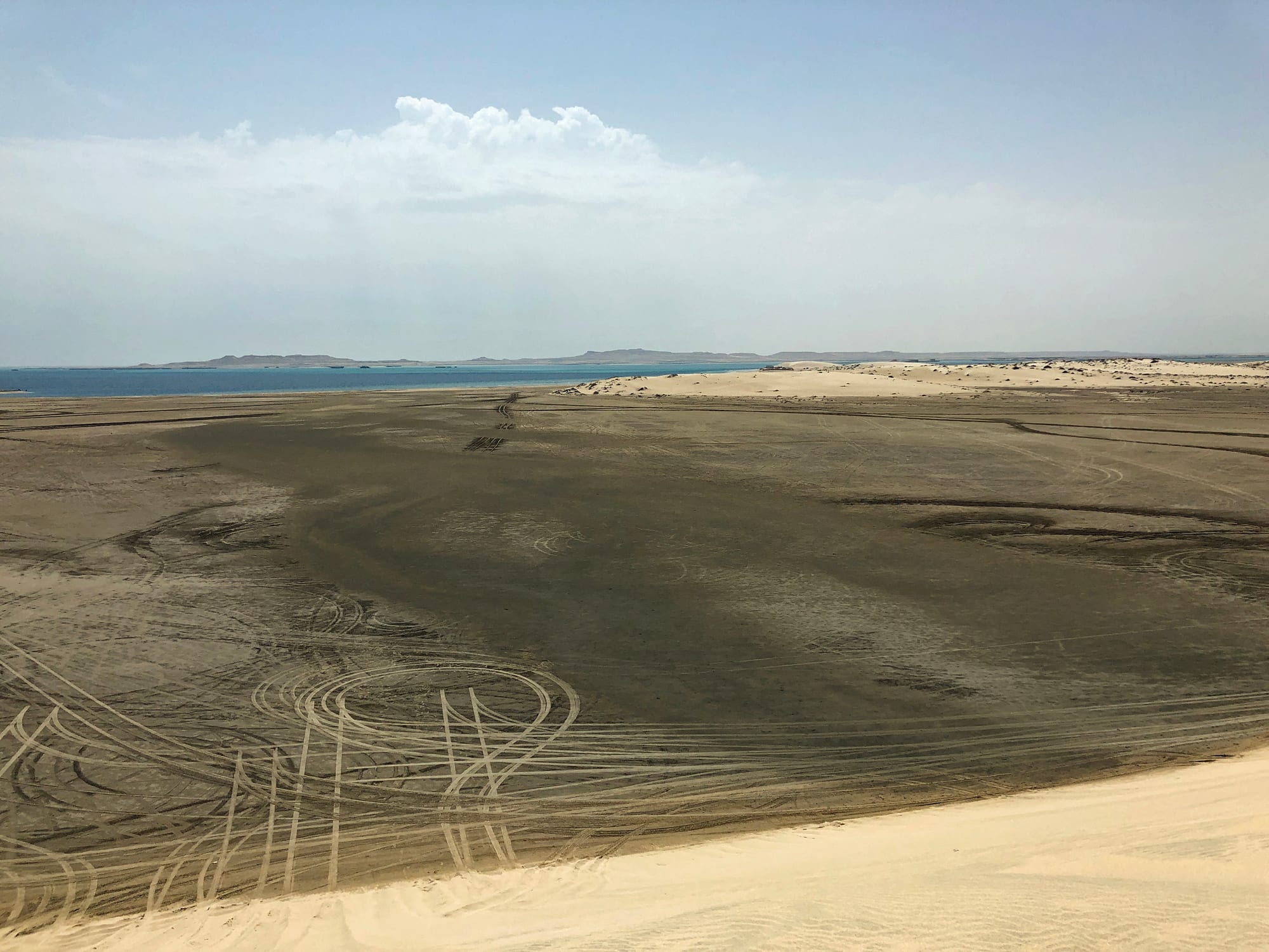 Sand dunes meeting a calm inlet of sea water in a desert landscape