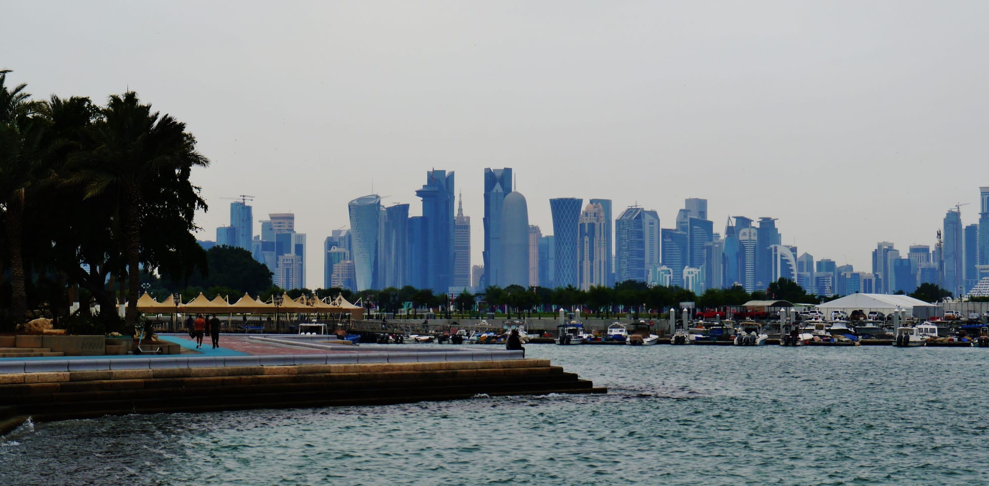 A curved waterfront promenade facing a dense modern skyline of skyscrapers