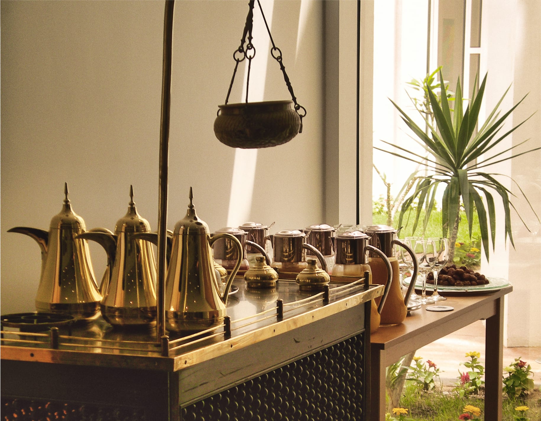 A pot of coffee, small cups and a bowl of dates on a table