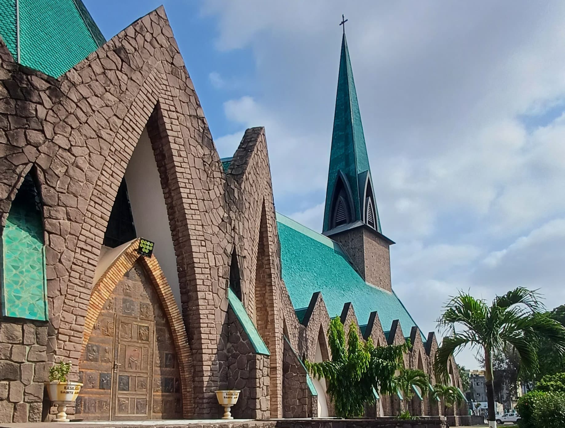 A modernist church with a distinctive striped green roof rising above a city