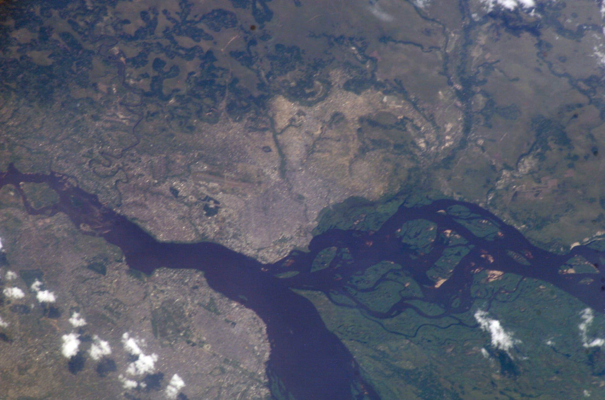 An astronaut photograph looking down on Brazzaville and Kinshasa facing each other across the wide brown Congo River