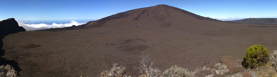 A vast volcanic caldera with a cone rising from a barren lava plain