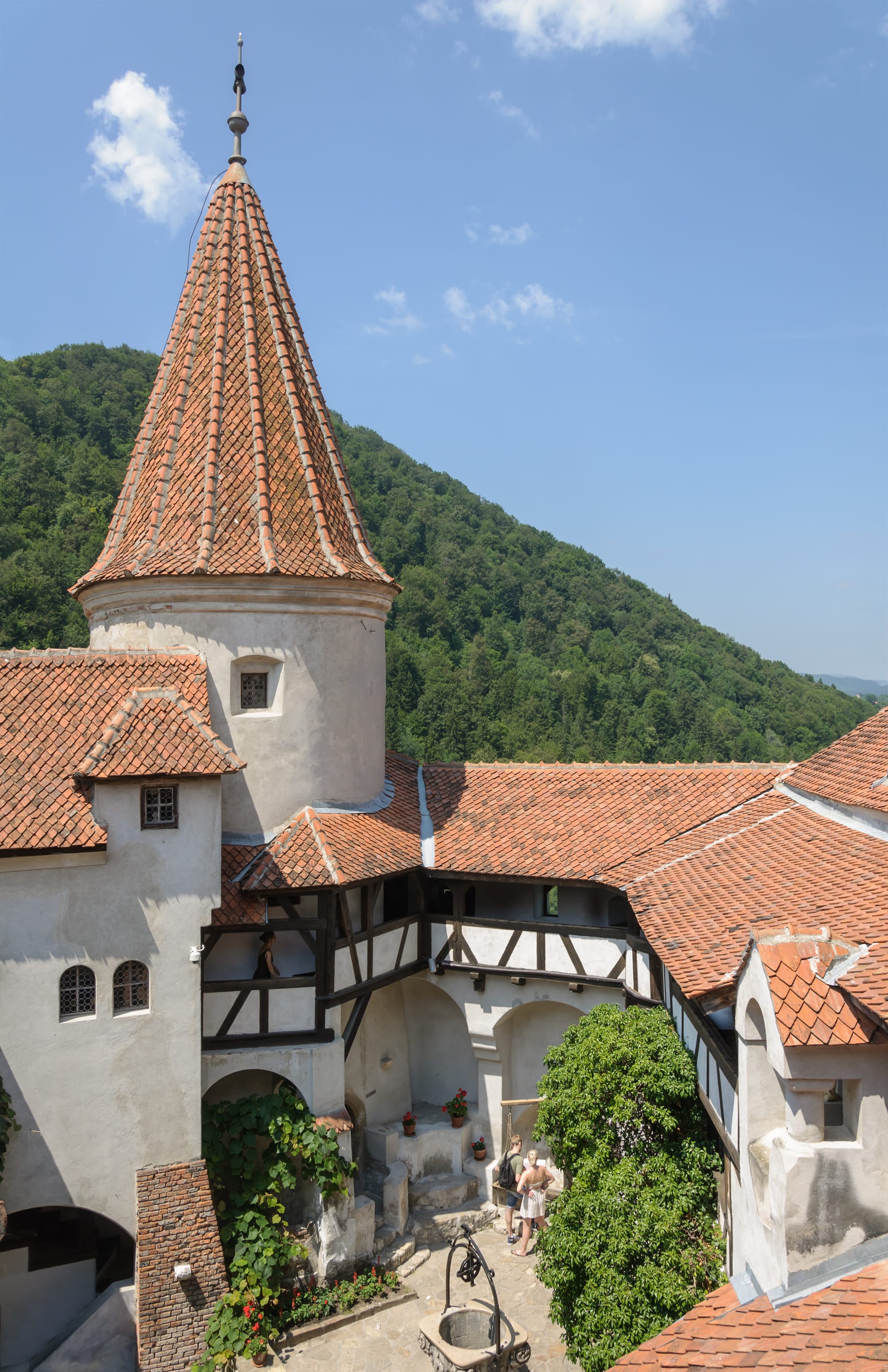 A stone castle courtyard with a round tower and steep roof